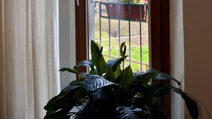 Una habitación con una puerta que da a un balcón con vistas a un jardín y montañas.