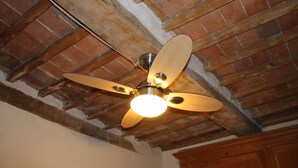 A ceiling fan with four blades, a light fixture, and exposed wooden beams. - House pe'L Ghetto (Pitigliano)