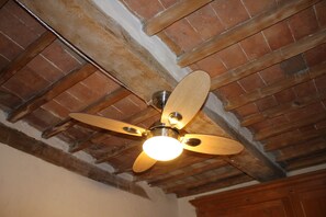 A ceiling fan with four blades, a light fixture, and exposed wooden beams.