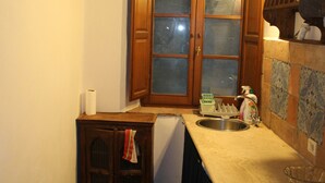 A kitchen with wooden cabinets, a window, and a sink. - House pe'L Ghetto (Pitigliano)