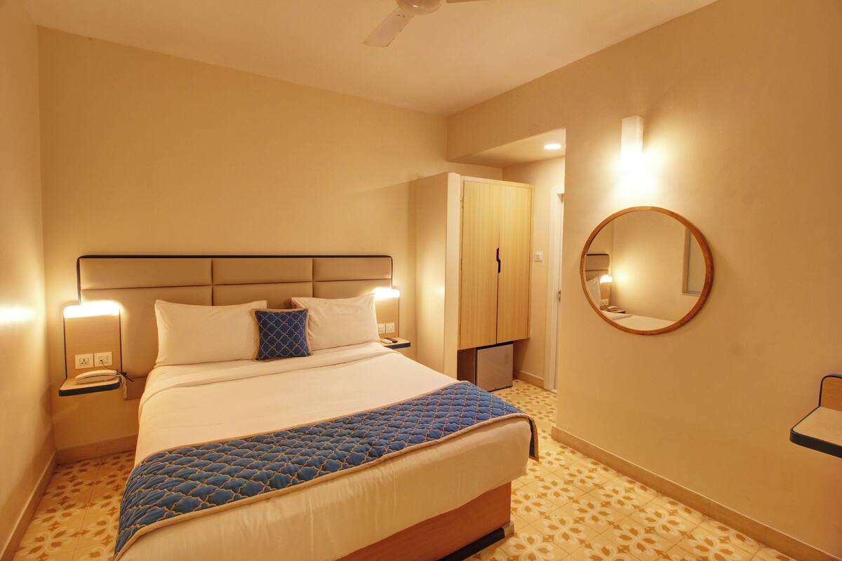 Ein Hotelzimmer mit Bett, Nachttischlampen, einem Spiegel und einem Kleiderschrank.