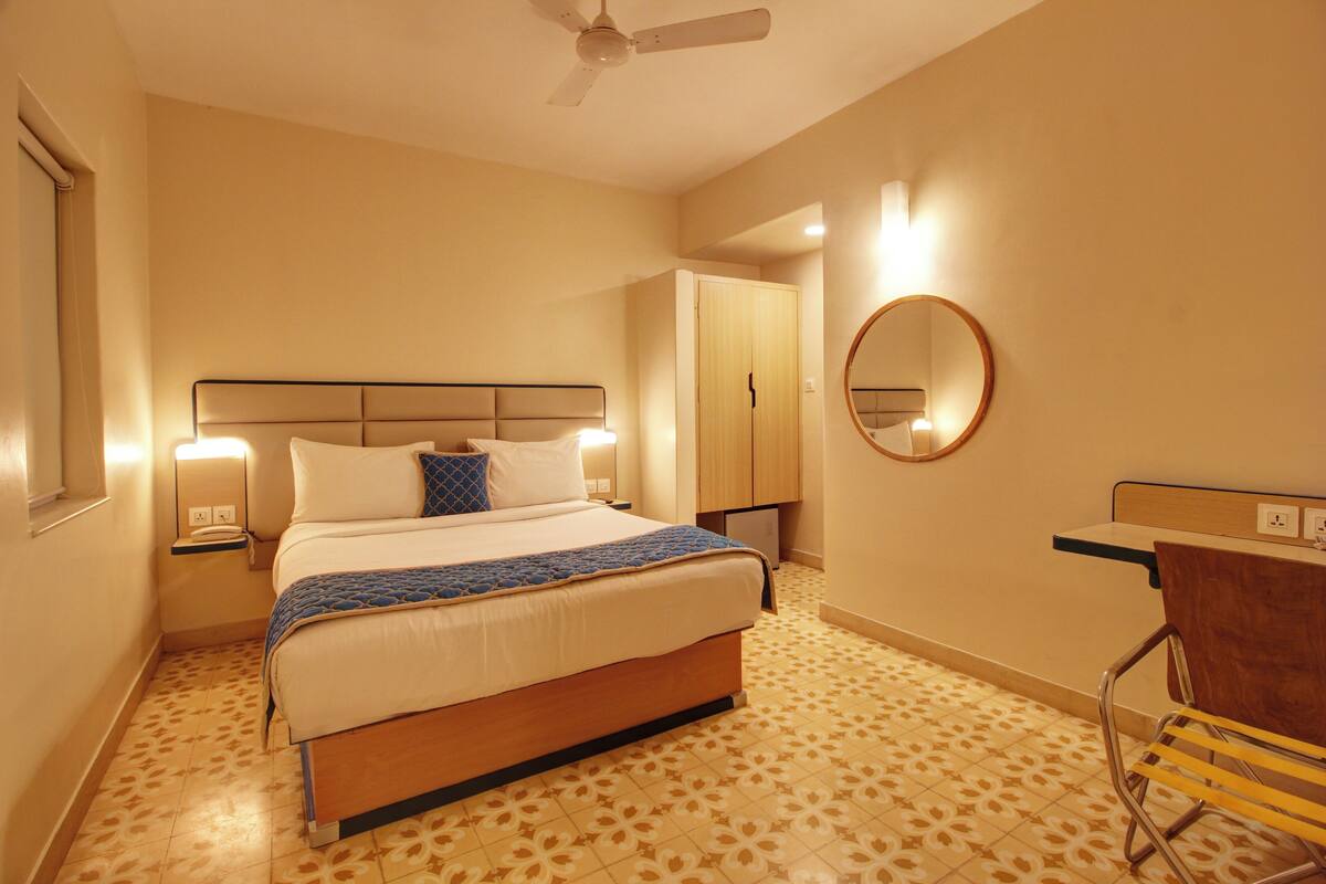 Ein Hotelzimmer mit Bett, Nachttisch, Lampe, Deckenventilator und Spiegel.