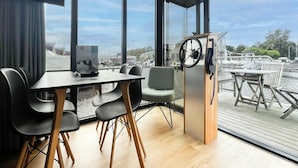 Une pièce moderne avec de grandes fenêtres, une table en bois, des chaises et un volant.