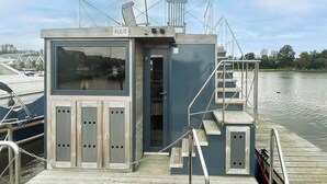 Une petite structure fermée, dotée d’une plaque signalétique, d’une porte et d’un escalier menant à un quai.