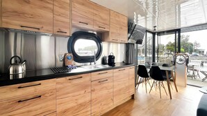 Une cuisine moderne avec des meubles en bois, une hotte de cuisine en acier inoxydable et une fenêtre donnant sur un quai.
