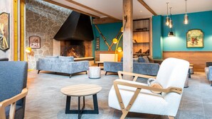 A cozy lounge area with sofas, a fireplace, and a stone wall.