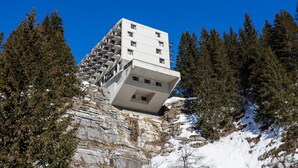 Ein modernes Gebäude mit einem markanten, vorspringenden Design, umgeben von einem Waldgebiet.