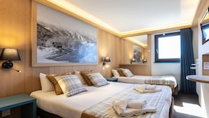 Une chambre d’hôtel avec deux lits, un grand tableau accroché au mur, des lampes de chevet, une petite table et une fenêtre avec des rideaux.