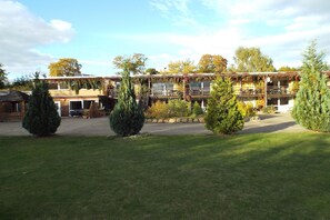 Ein Motel mit mehreren Zimmern, einem überdachten Außenbereich und einem gepflegten Rasen.
