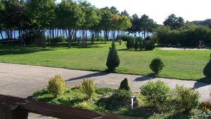 A well-maintained lawn with a wooden deck, a clear view of the water, and a swing set. - Mobile Home im Ferienpark mit Seezugang (Dabel)