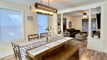 Un espace repas comprenant une longue table, des chaises et un luminaire suspendu.