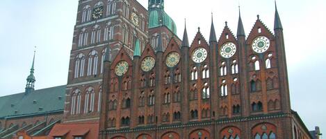 A historic building with multiple spires and large clocks, featuring Gothic architecture.