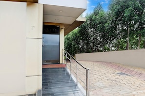 A building entrance with a metal railing, a tiled walkway, and a door leading to an interior. - Cosy Stays at Durg Near Railway Station (Durg)