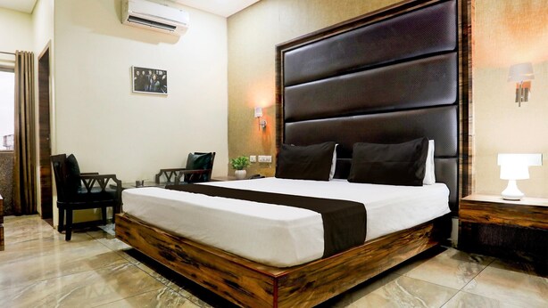 A bedroom with a large bed, a desk, a chair, and an air conditioning unit. - Cosy Stays at Durg Near Railway Station (Durg)