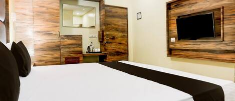 Une chambre d’hôtel avec un lit, une tête de lit en bois, un téléviseur fixé au mur et un miroir au-dessus du lit.