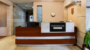 A reception desk labeled 'TOWNHOUSE Company-Serviced' with a clock, a chandelier, and a wall-mounted fan. - Cosy Stays at Durg Near Railway Station (Durg)