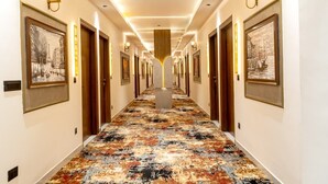 Un corridoio d'albergo con quadri appesi alle pareti, una moquette decorata e un pilastro centrale.