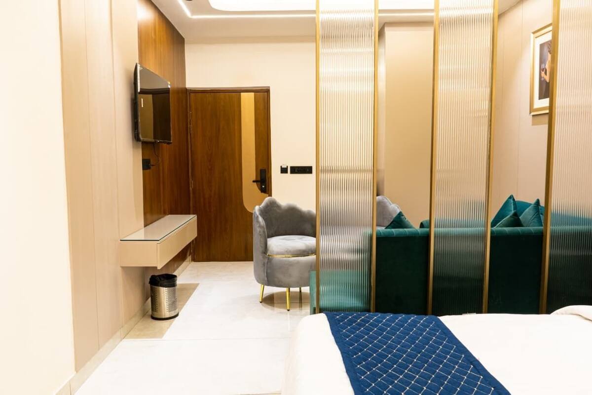 Ein Hotelzimmer mit einem Bett, einem Fernseher, einem Sessel, einer Couch und einem Papierkorb.