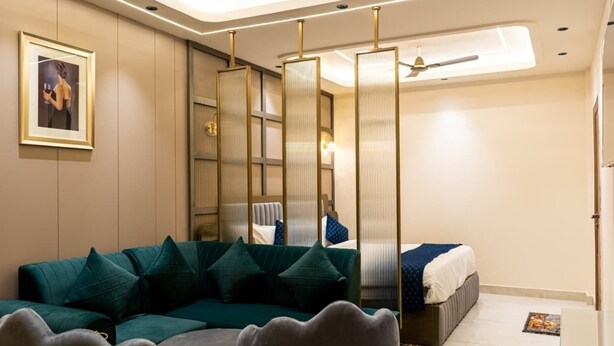 Una camera da letto moderna con un divano verde, un letto con biancheria azzurra e una ventola a soffitto.