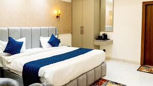 Una camera d'albergo con un letto, un armadio, uno specchio, un lavandino e una porta.