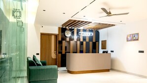Un'area di accoglienza dal design moderno, con una reception, un divano verde e una ventola a soffitto.