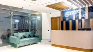 Una reception dal design moderno, un divano color petrolio e un muro in vetro.