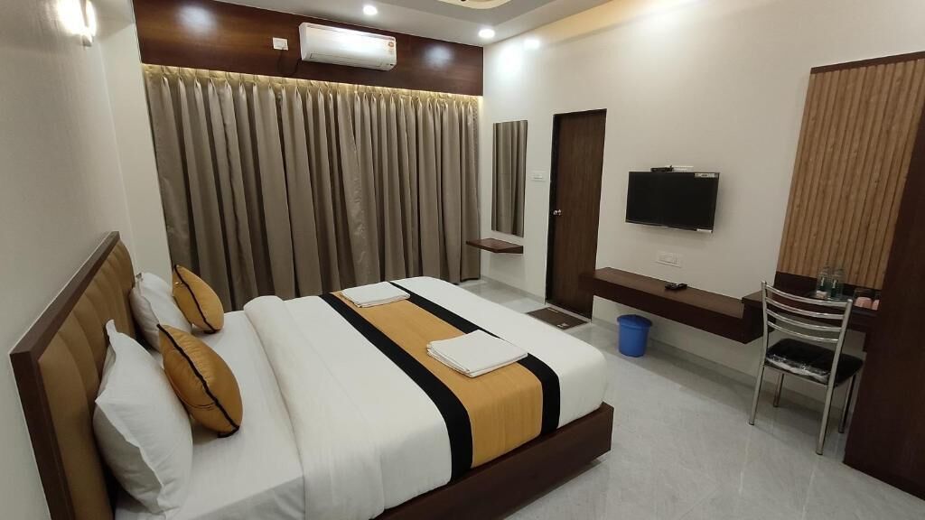 Una habitación de hotel con una cama, televisión, escritorio y una silla.