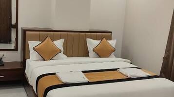 A modern hotel room with a bed, nightstands, a ceiling fan, and recessed lighting.