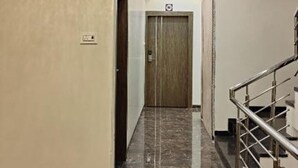 A hallway with a marble floor, a chandelier, and a staircase. - Hotel Grand Lushwood (Chhatrapati Sambhajinagar)