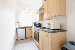 Eine kleine Küche mit Geschirrspüler, Herd, Backofen und Toaster.