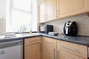 Eine Küche mit Holzausstattung, einer schwarzen Arbeitsplatte, einer Mikrowelle und einer Kaffeemaschine.