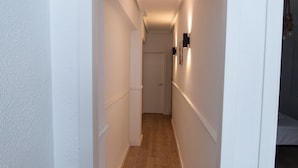 A narrow hallway with white walls and wooden flooring leading to a door. - Beautiful Apartment by the sea in Almeria (Almeria)