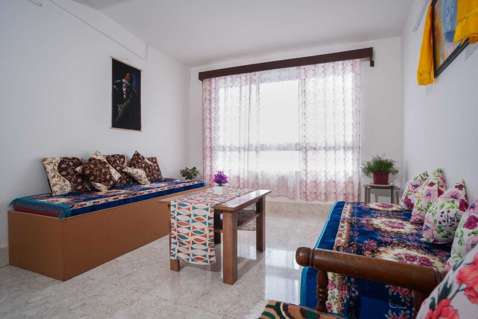A living room with a sofa, a wooden table, and a patterned rug.