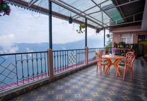 A terrace with a table and chairs, a railing, and potted plants. - Himavati Retreat Homestay (Darjeeling)