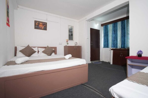 A bedroom with a bed, a dresser, a mirror, and a window with curtains. - Himavati Retreat Homestay (Darjeeling)