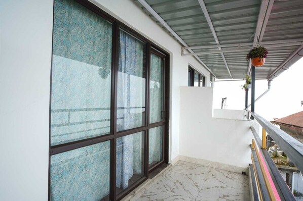 A balcony with a tiled floor, a metal roof, and a window with a curtain. - Himavati Retreat Homestay (Darjeeling)