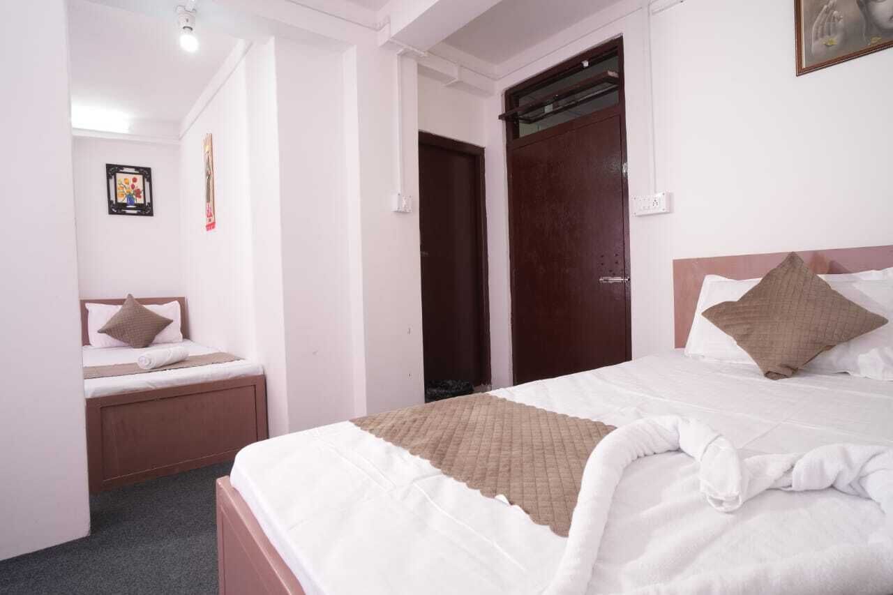 Une chambre d’hôtel avec un grand lit, un lit plus petit et une armoire.