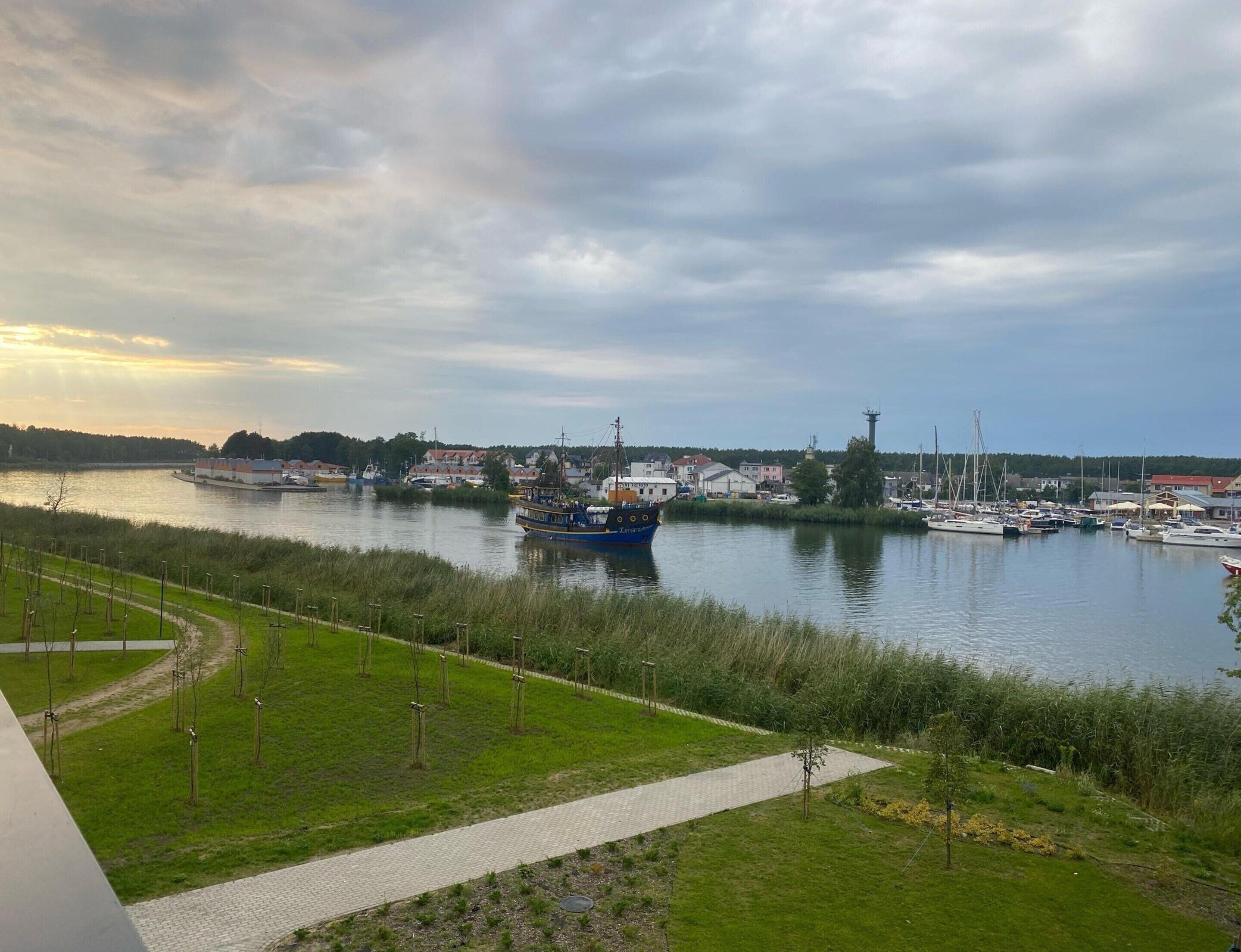 Une vue sur le fleuve, avec des bateaux, un sentier et des bâtiments en arrière-plan.
