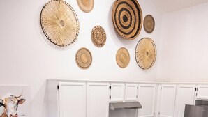 Una cocina moderna con armarios blancos, un refrigerador de acero inoxidable y detalles decorativos de fibra natural.