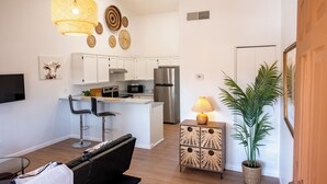 Una cocina moderna con armarios blancos, electrodomésticos de acero inoxidable y una isla central con taburetes de bar.