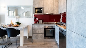 A modern kitchen with a built-in oven, microwave, and red backsplash. - Modern Beachfront Escape, Calahonda (Mijas)