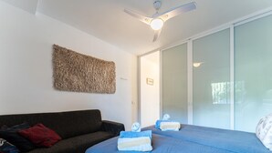 A bedroom with a bed, a dark-colored sofa, a ceiling fan, and a large window. - Modern Beachfront Escape, Calahonda (Mijas)