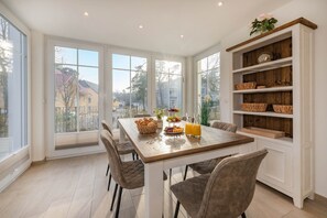 A dining area with a wooden table, cushioned chairs, and a white cabinet with wicker baskets. - Domizil Parkstraße Bella Katja 02 - Quiet campsite near the beach on Usedom (Kölpinsee)