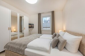 Ein Schlafzimmer mit Bett, Kleiderschrank, Fenster und einem Bild an der Wand.