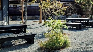 A courtyard with trees, a stone wall, and a building with a sloped roof. - SAKURAHOTEI (Hakone)