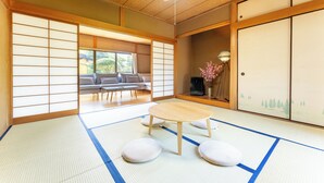 A tatami mat room with a low wooden table, cushions, a sofa, and sliding doors. - SAKURAHOTEI (Hakone)