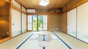 A tatami mat room with a round table and cushions, wooden beams, and shoji screens. - SAKURAHOTEI (Hakone)