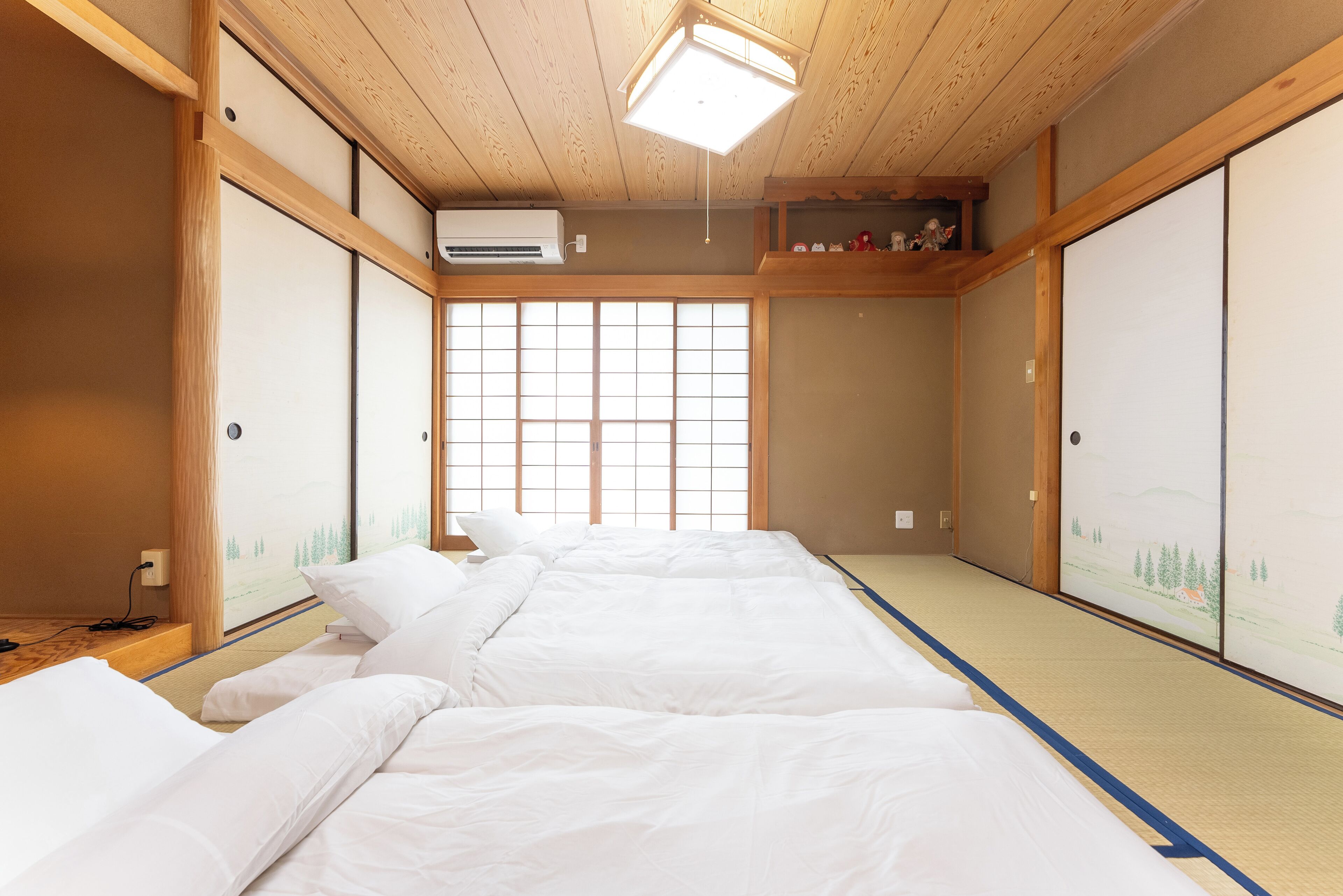 Una habitación tradicional japonesa con suelo de tatami, un panel shoji y una cama futón.