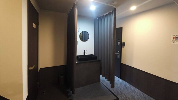 A hotel restroom with a sink, a mirror, and a sign indicating the restroom. - HOTEL STAY Plus (Imabari)