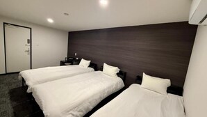 A hotel room with two beds, a dark wooden headboard, a white door, and a carpeted floor. - HOTEL STAY Plus (Imabari)